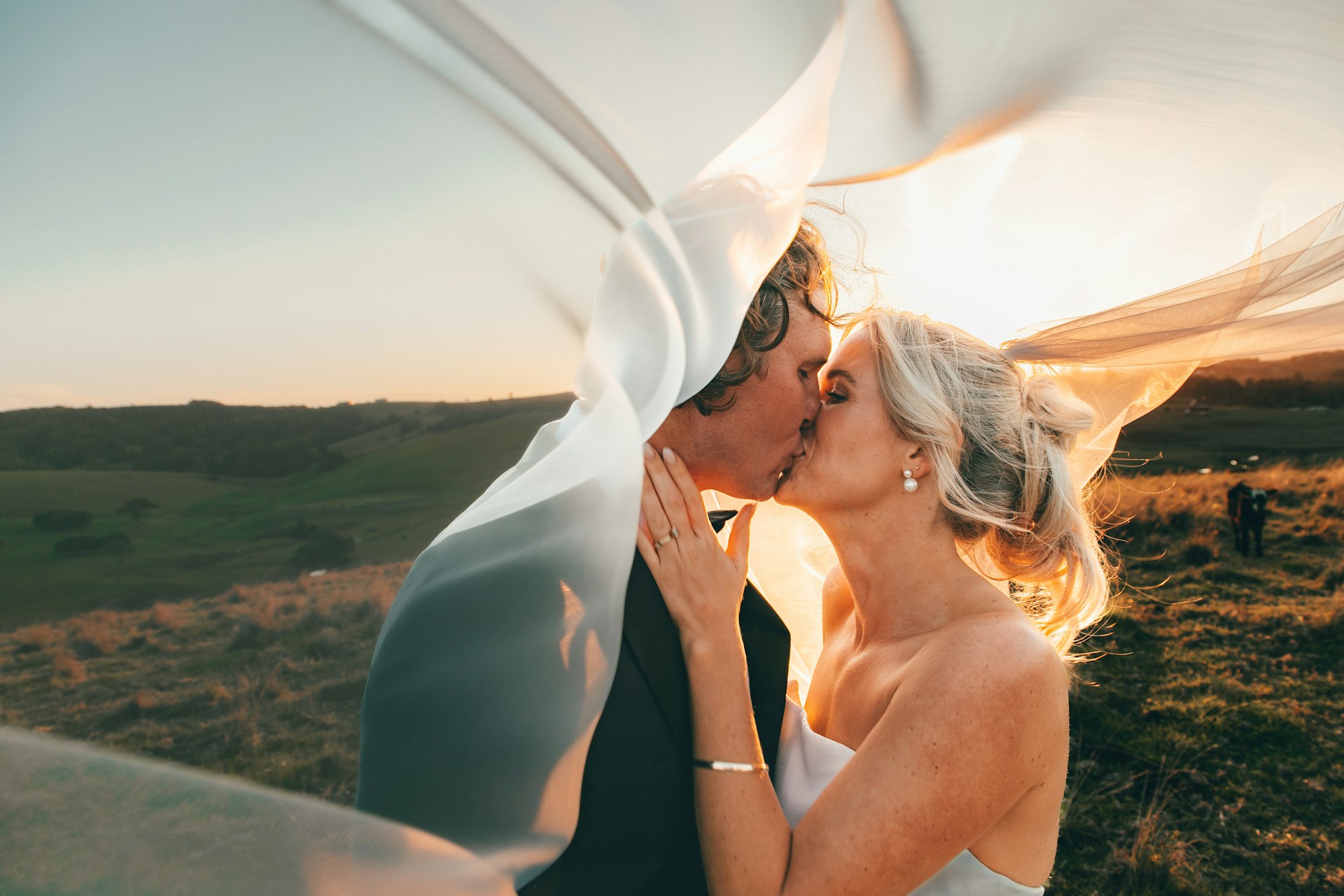 A couple embraces lovingly on a rustic wooden bridge.